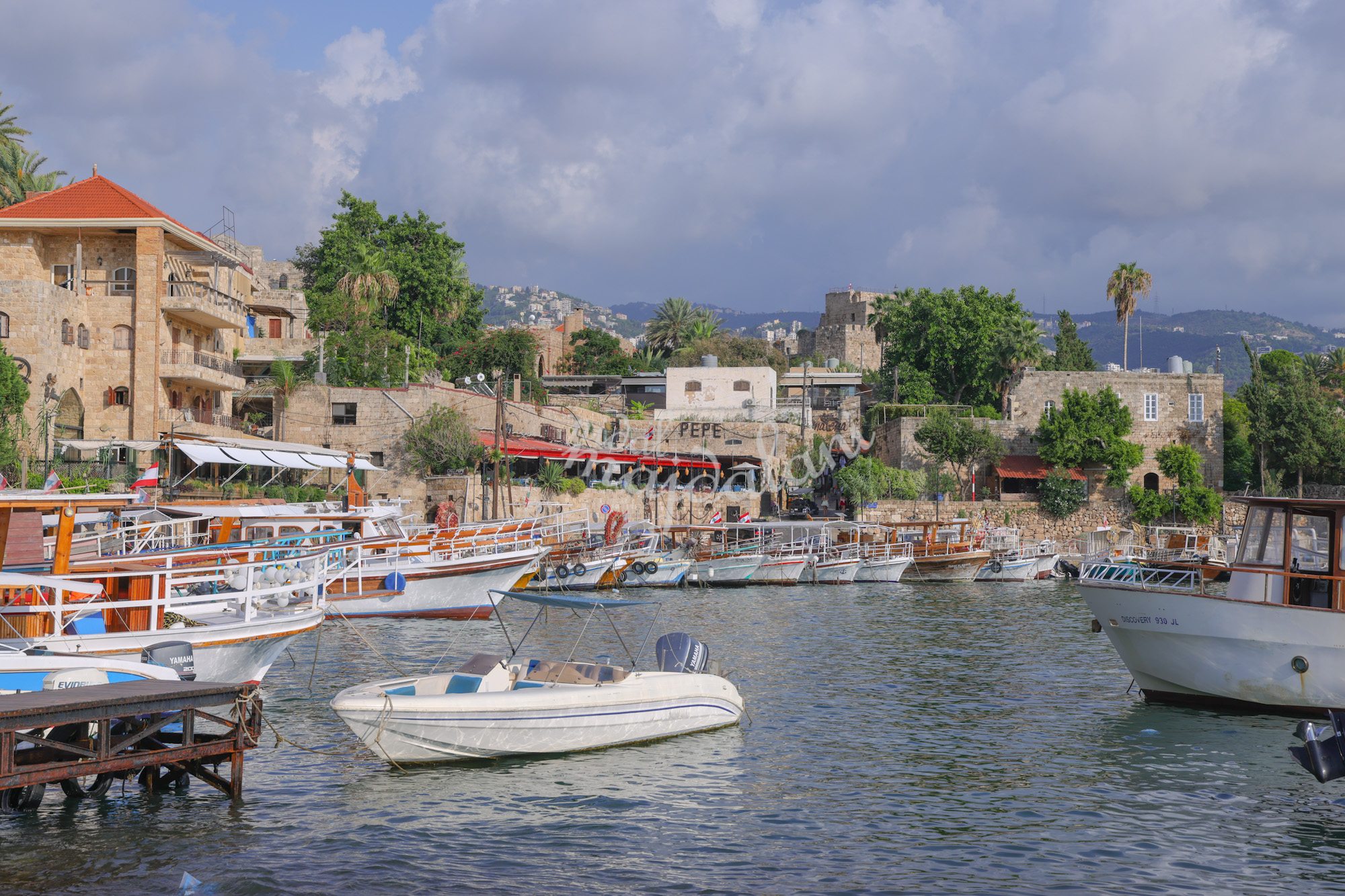 Old harbor of Byblos with fishing boats and stone buildings